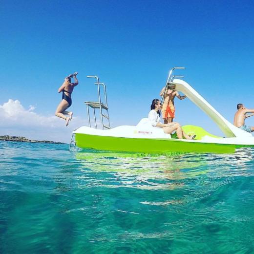 People enjoying a pedal boat with a slide in the sea.