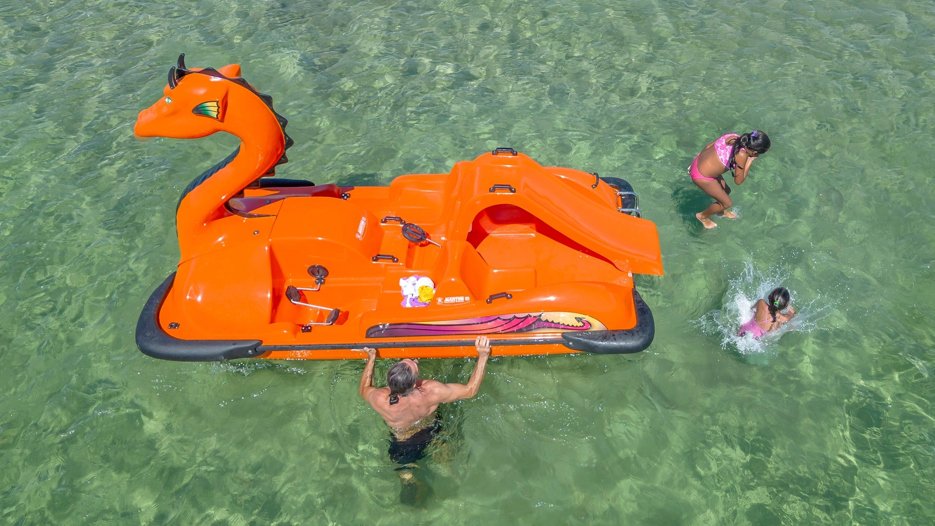 Spiaggia con ombrelloni, pedalò e acque cristalline, ideale per il relax estivo.