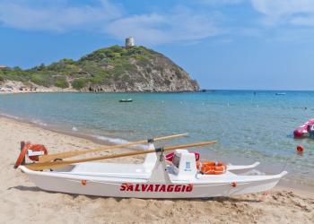 Catamarano rosso con remi e salvagente galleggia sull'acqua tranquilla.