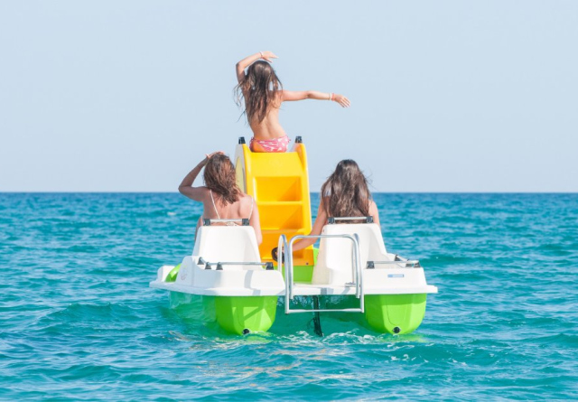 Tre persone su un pedalò verde in mare.